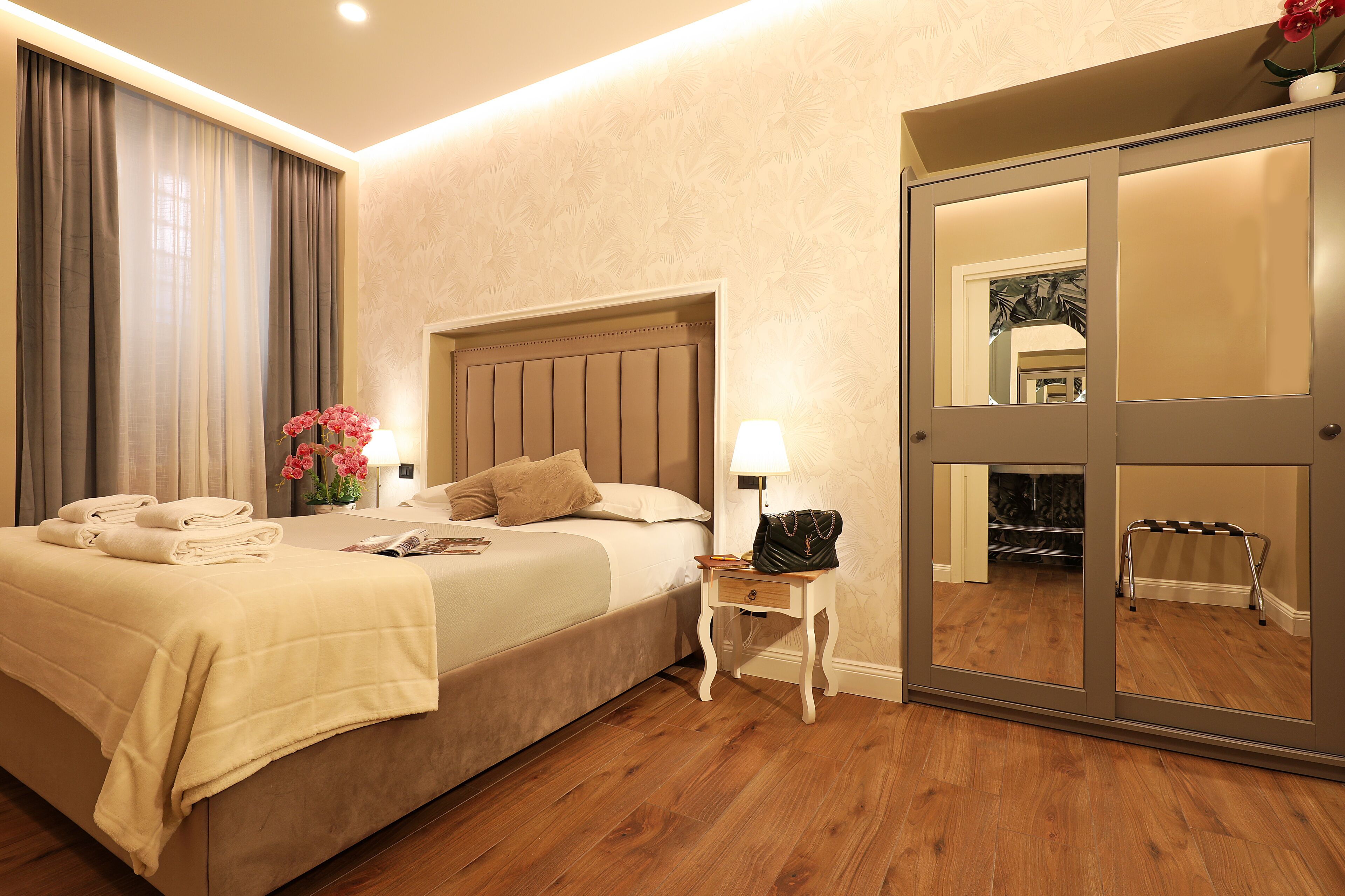 Une chambre d’hôtel comprenant un lit, une table de chevet, une lampe et un meuble avec miroir.