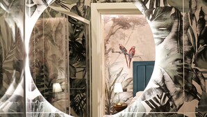 A bathroom with a large mirror, a blue door, and a wall with a tropical leaf pattern. - Vatican Cozy Suites (Rome)