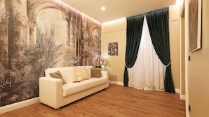 A living room with a large mural, a white sofa, and a wooden floor. - Vatican Cozy Suites (Rome)