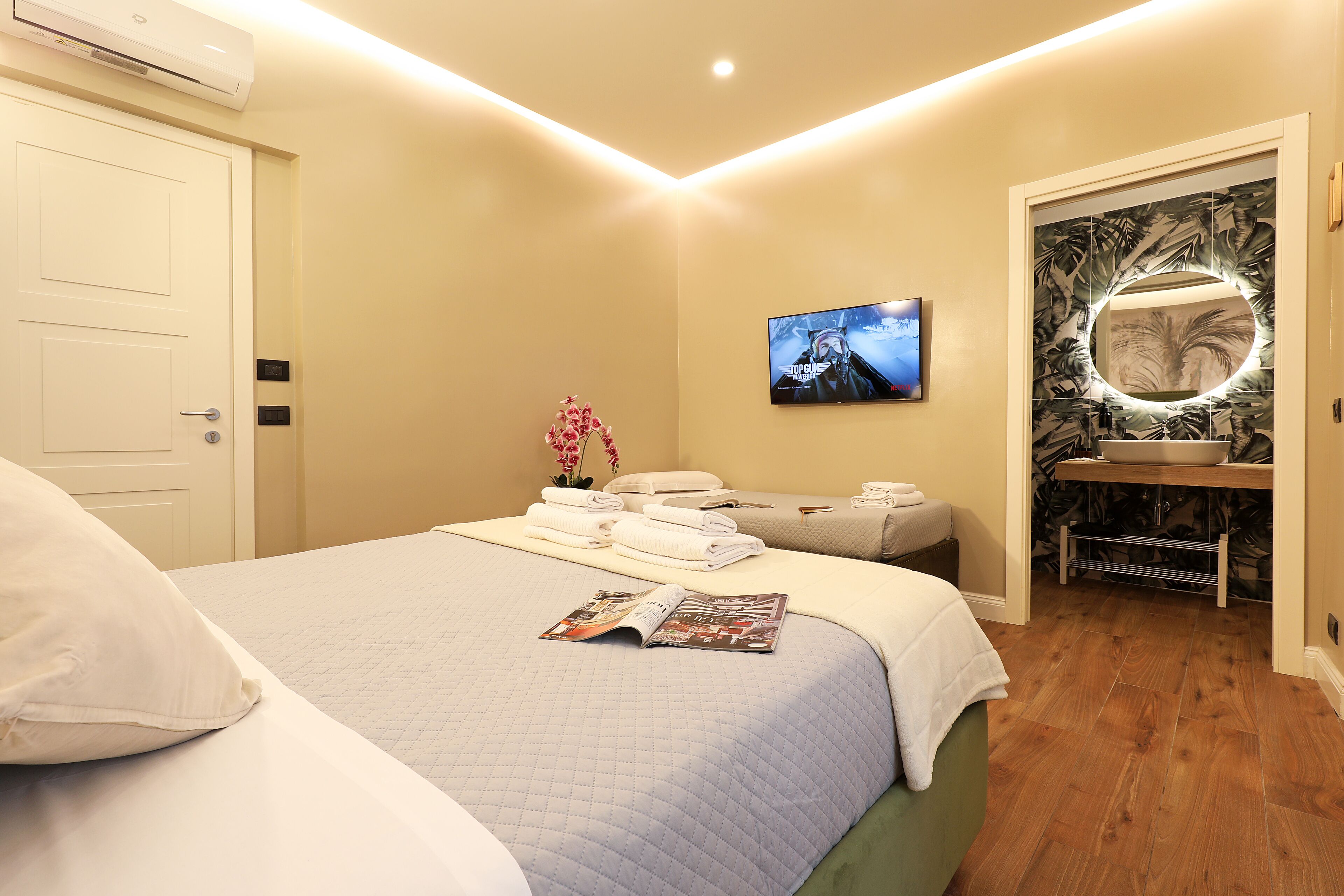 A hotel room with a bed, a TV, a bathroom with a mirror, and a sink.