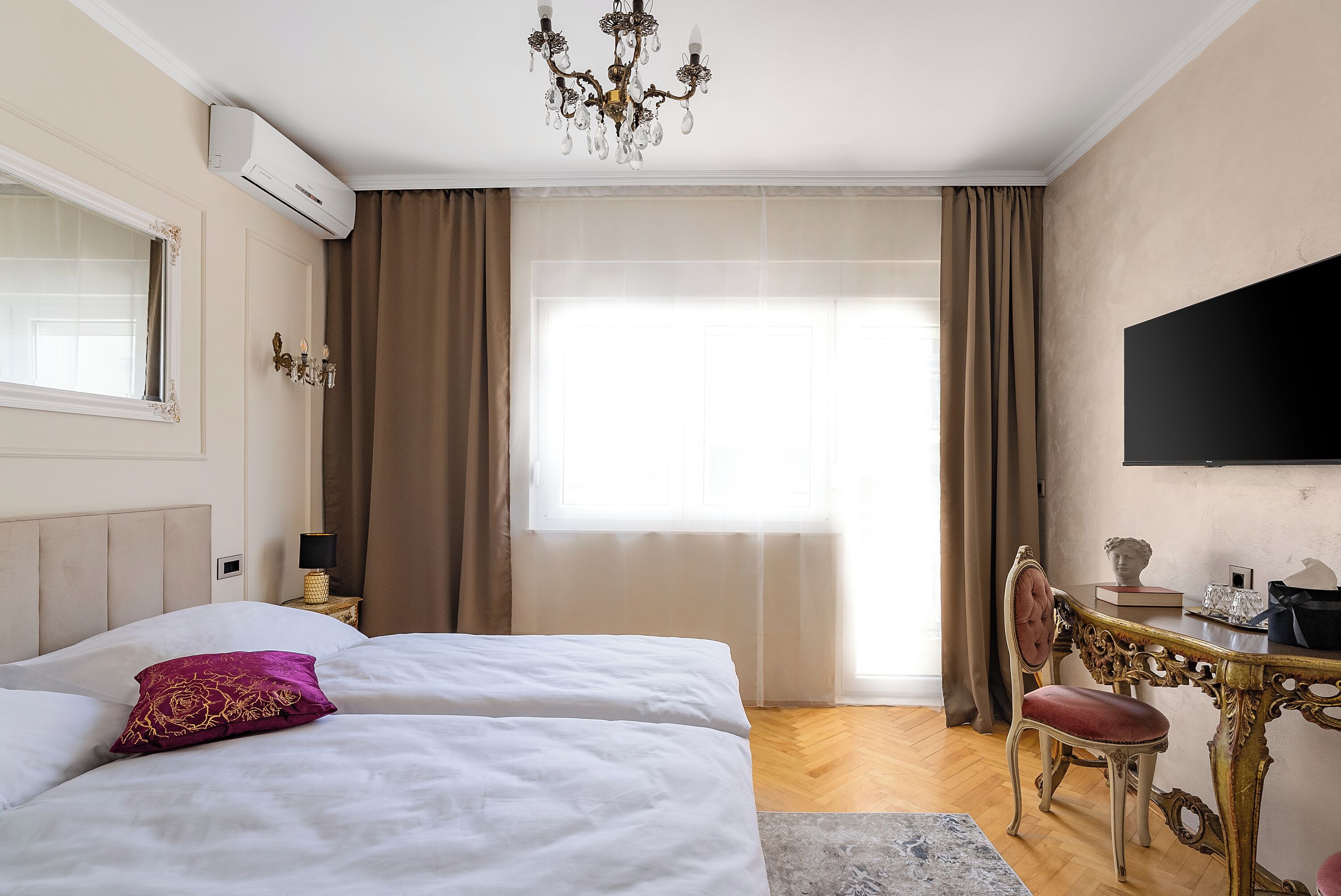 Ein Hotelzimmer mit Bett, Schreibtisch, Stuhl, Fernseher und einem Fenster mit Vorhängen.