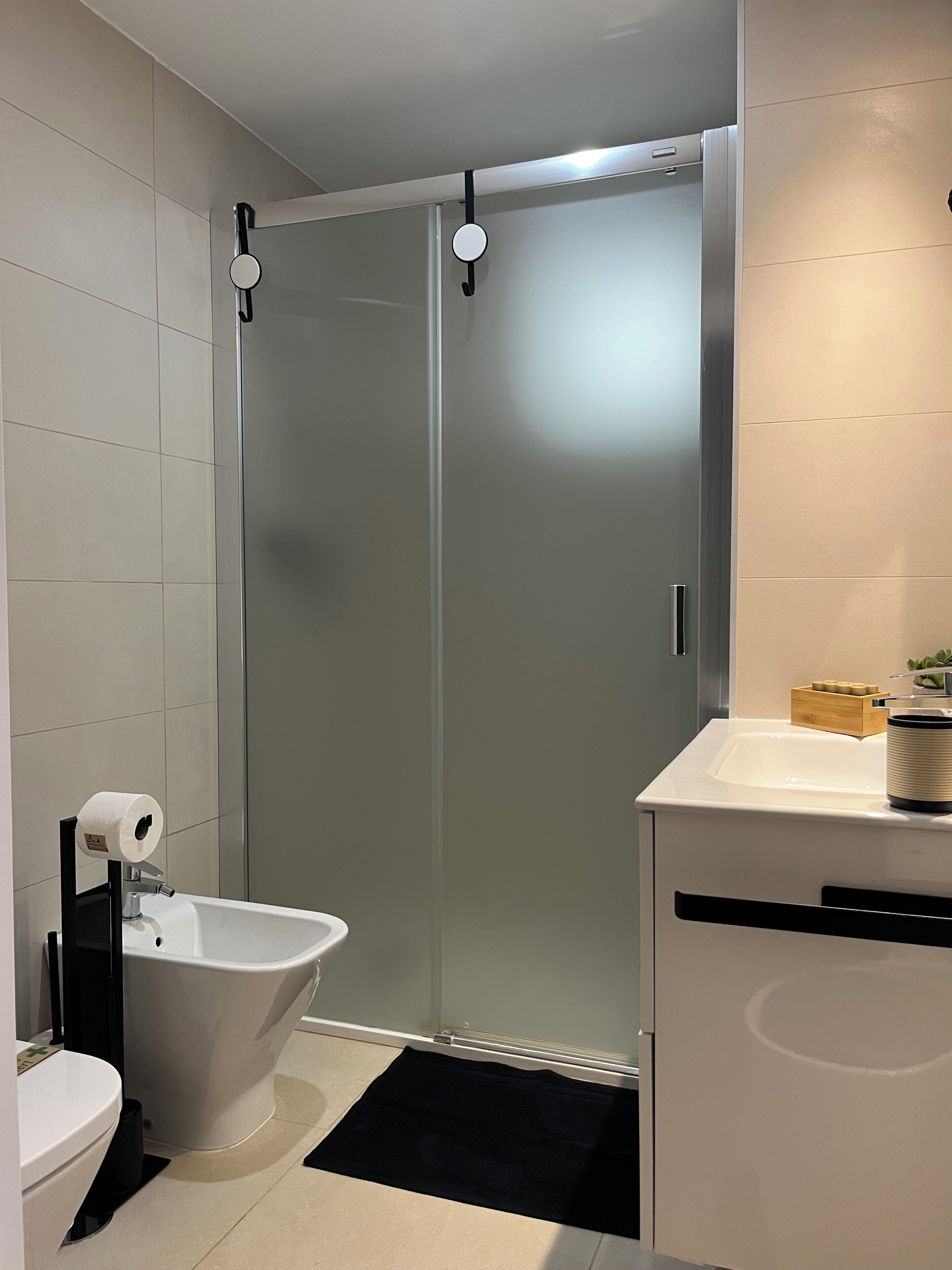 Ein modernes Badezimmer mit Toilette, Bidet und einer Duschkabine aus Glas.