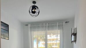 Une chambre à coucher avec un lit, une table de chevet, une lampe et une vue sur l’extérieur.