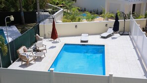 A rooftop pool area with lounge chairs, a small table, and umbrellas. - Townhouse w/Pool Near Beach, Airport & Supermarket (Nassau)