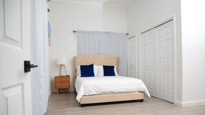 A bedroom with a bed, a nightstand, a lamp, and a wardrobe. - Townhouse w/Pool Near Beach, Airport & Supermarket (Nassau)
