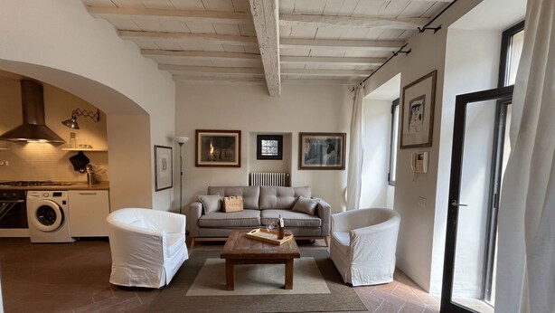 A living room with a sofa, two armchairs, a coffee table, and a kitchen area with a washing machine. - Your Terrace in Fiesole (Fiesole)