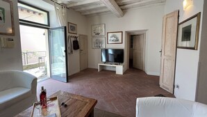 A living room with a white sofa, a wooden coffee table, a TV, and a door leading to another room. - Your Terrace in Fiesole (Fiesole)