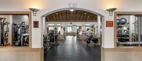 A gym with a wide entrance, various exercise equipment, and a sign indicating a maximum occupancy of 75 people.
