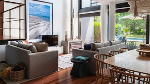 Un saló modern amb una finestra gran, un televisor de pantalla plana, un sofà i una zona de menjador amb caires de fusta.