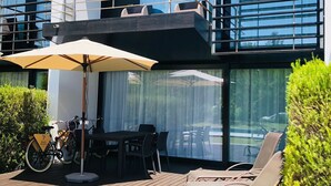 A modern outdoor patio with a table and chairs, a bicycle, and a lounge chair area.