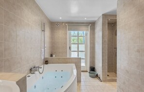 Bathroom features a bathtub, shower area, and door to a bright space.