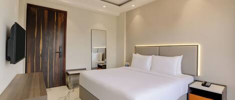 Una habitación de hotel moderna con una cama grande, mesitas de noche, un televisor y una puerta de madera.