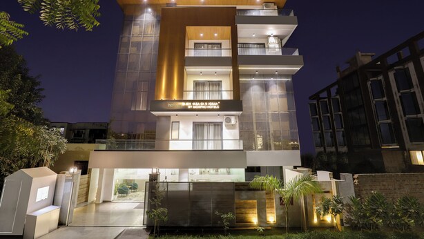 Un hôtel moderne doté d’une façade en verre, de nombreux balcons et d’une entrée bien éclairée.