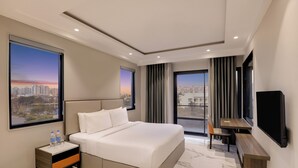 Une chambre d’hôtel moderne dotée d’un grand lit, d’un bureau, d’une télévision et offrant une vue sur la ville.