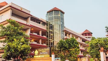 A multi-story hotel with a prominent glass tower, a sign for Gazebo Resort Pattaya, and lush greenery around the property.