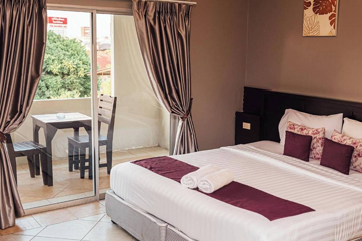 A hotel room with a bed, a table, and chairs near a sliding glass door.