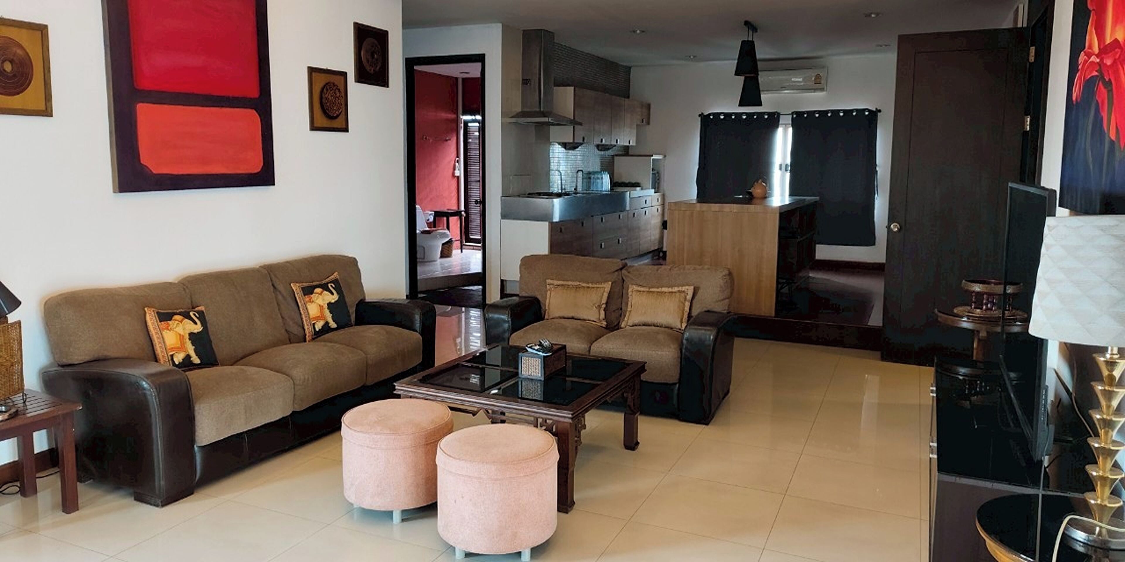 A living room with a sofa, ottomans, a coffee table, and a TV stand.