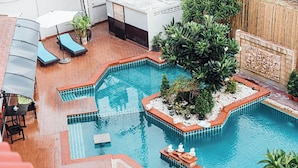 Ein Dachpool mit gefliesten Rändern, Liegestühlen und Topfpflanzen.