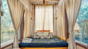 Une chambre confortable avec un lit, des rideaux et une vue sur l’extérieur.