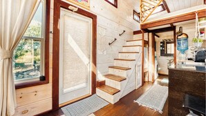 Un intérieur en bois avec un escalier, un coin cuisine et une vue sur l’extérieur.