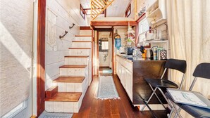 Une cuisine compacte avec un escalier en bois, un petit coin repas et un distributeur d’eau visible.