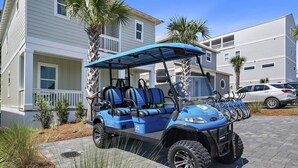 Ein Anwesen direkt am Strand mit befestigter Auffahrt, einem Golfwagen und einem weißen Gebäude mit Balkon.