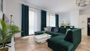 Ein modernes Wohnzimmer mit einem grünen Sofa, einem weißen Couchtisch und einer Topfpflanze.