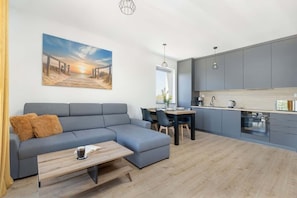 A modern living room with a sofa, a coffee table, and a dining area with chairs.