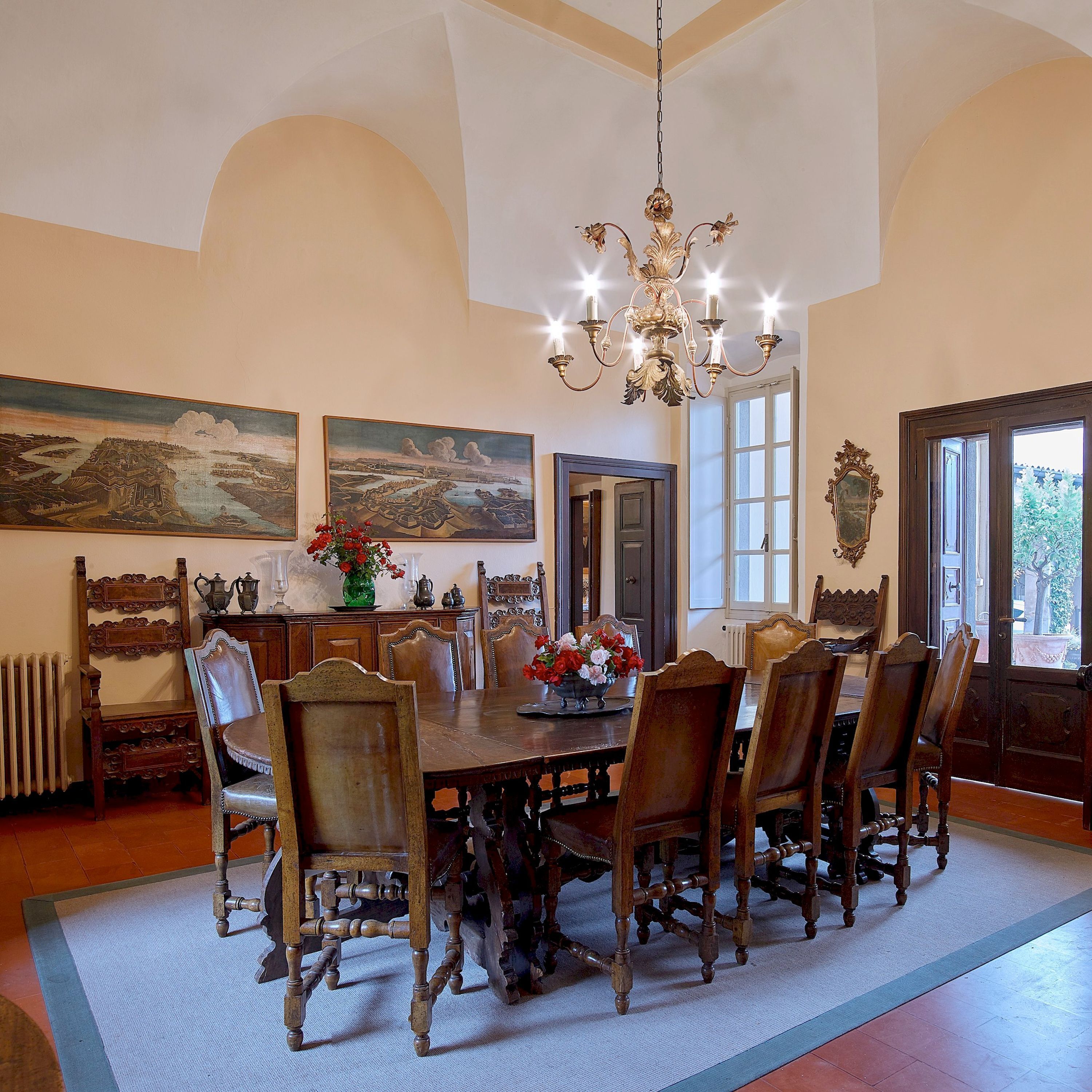 Ein Esszimmer mit einem großen Tisch, Stühlen, einer Kronleuchter und Kunstwerken an den Wänden.