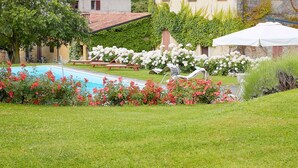 A villa with a swimming pool, surrounded by lush gardens and a mountainous backdrop.