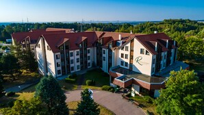 Ein großes, mehrstöckiges Hotel mit rotem Ziegeldach, umgeben von viel Grün und blauem Himmel.