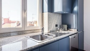 Cozinha moderna com bancadas de granito, pia de aço inoxidável e armários azuis.