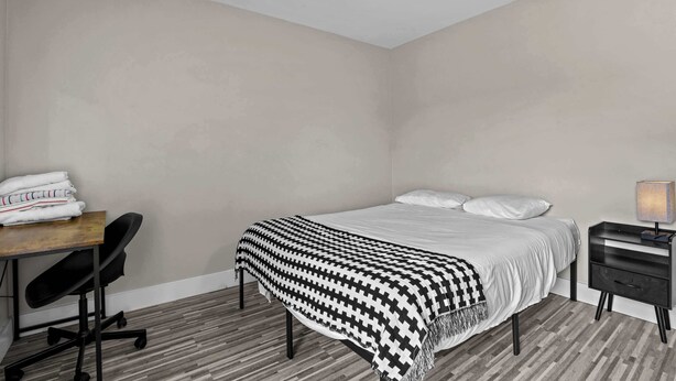 Une chambre d’hôtel comprenant un lit, un bureau, une chaise, une table de chevet et une lampe.