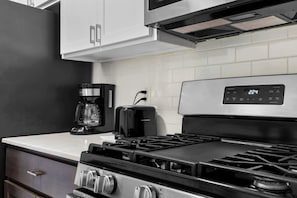 A kitchen with a stove, a coffee maker, and a toaster. - Your Home Away From Home in Rochester Hills! (Rochester Hills)