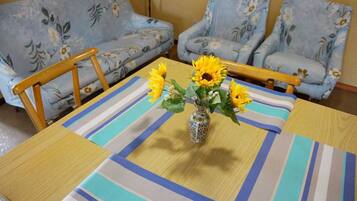 Ein Esstisch mit gestreiftem Tischtuch, umgeben von Sofas mit Blumenmuster.