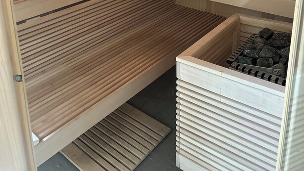 Un sauna avec des bancs en bois, une horloge et un panneau de commande.