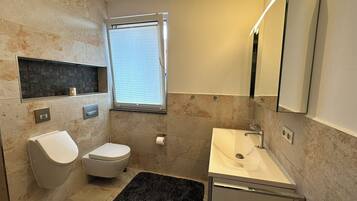 Une salle de bain moderne avec des toilettes, un lavabo et une fenêtre.
