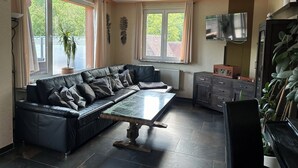 Un salon moderne avec un canapé d’angle, une table basse en marbre et un téléviseur.