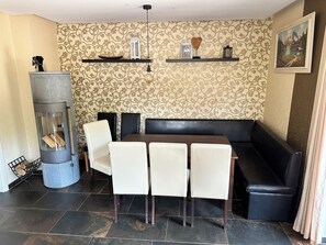 A dining area with a table and chairs, a fireplace, and decorative shelves.
