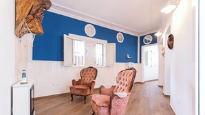 A hallway with two plush armchairs, a wooden cabinet, and a decorative wall piece. - La Bussola (Las Palmas de Gran Canaria)