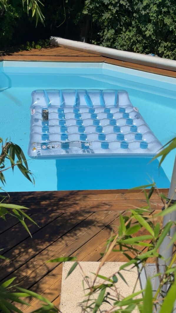 A swimming pool with a blue inflatable deck and a wooden deck surrounding it.