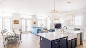 A modern kitchen with a central island, white cabinetry, and pendant lighting. - Luxurious Getaway in CS South with access to 20+ resort like amenities (Port Aransas)