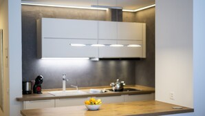A modern kitchen with a wooden countertop, a bowl of fruit, and a stainless steel sink. - CHASA TULAI F83: BEAUTIFULLY RENOVATED STUDIO IN HOLIDAY PARK TULAI F83 (Scuol)