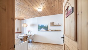 A wooden-paneled room with a herringbone floor, a dining table with chairs, a hanging light fixture, and a framed picture on the wall. - Chasa Vi Studio: located in the center of Scuol (Scuol)
