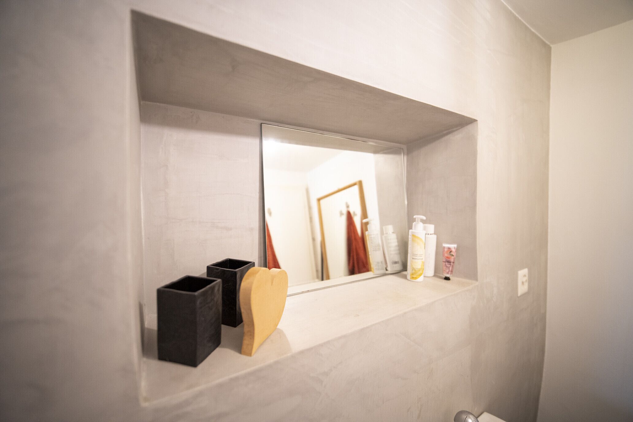 Een badkamer met een marmeren aanrecht, een spiegel en toiletartikelen.