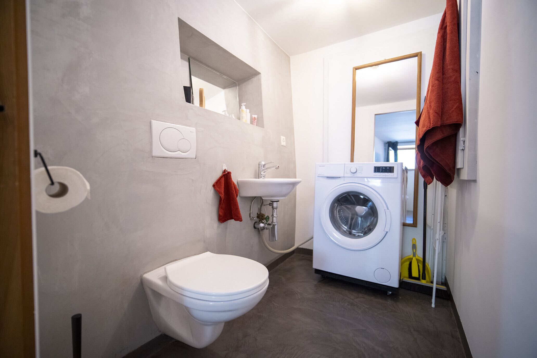 Une salle de bain moderne équipée de toilettes, d’un lavabo et d’un lave-linge.