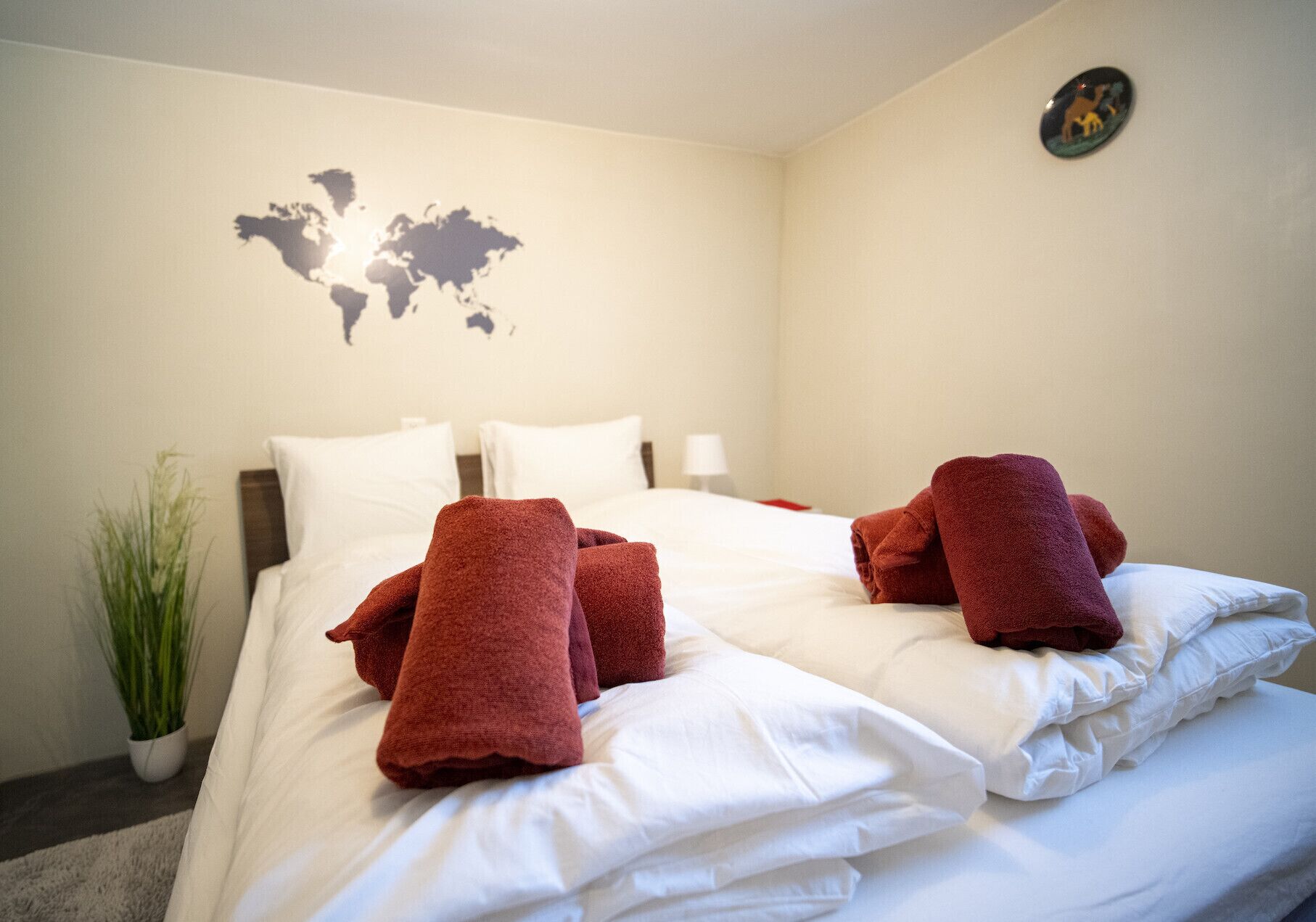 Une chambre d’hôtel avec un lit, du linge de lit blanc et des serviettes rouges.