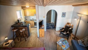 A compact living space with a kitchenette, a dining area, and a seating area with a sofa and a chair. - CHASA GISEP STUDIO: HOLIDAYS IN SCUOL, THAT MEANS RELAXATION IN A TYPICAL ENGADIN VILLAGE! (Scuol)