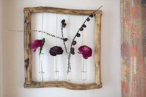 A rustic wooden frame with glass vases containing flowers and pinecones. - Chasa Grusaida: Charming, cosy 2-room flat with balcony near the golf course (Vulpera)