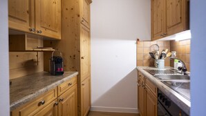 Una cocina compacta con armarios de madera, encimera de granito, estufa y pileta.